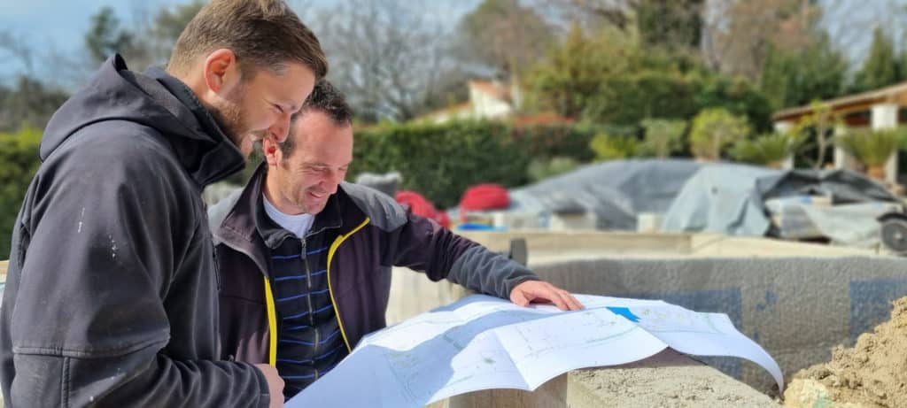 Deux experts en aménagement paysager sur un chantier, consultant un plan du projet.