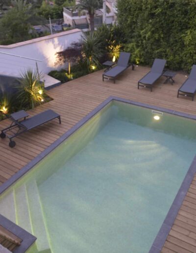 Aerial view of a rectangular pool surrounded by a wooden deck with sun loungers