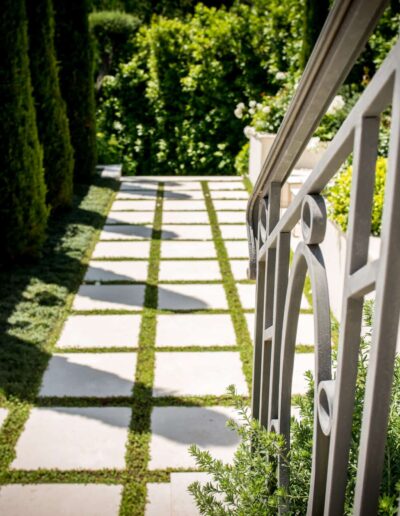 Allée en dalles et garde-corps en métal dans un jardin soigné