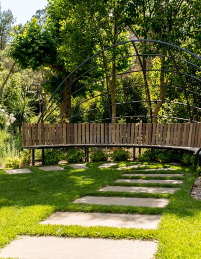 Banc courbe sous une pergola métallique au cœur d’un jardin naturel à Mougins