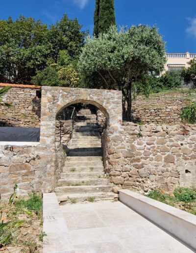 Stone arch and steps in a terraced garden before renovation