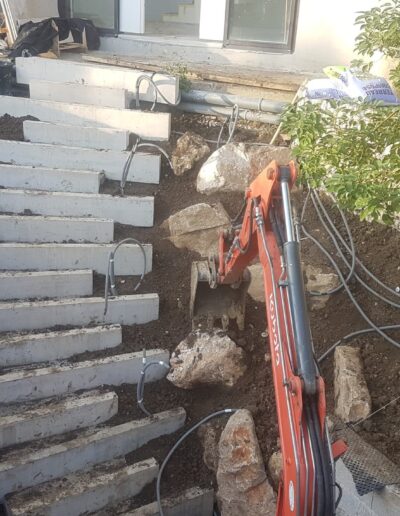 Installation of concrete steps on a sloped terrain during garden construction.