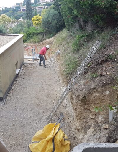 Ground preparation and earthwork at the base of a slope before landscaping.