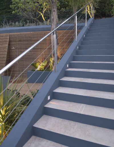 Escalier extérieur moderne avec rambarde en inox donnant sur une terrasse bois aménagée