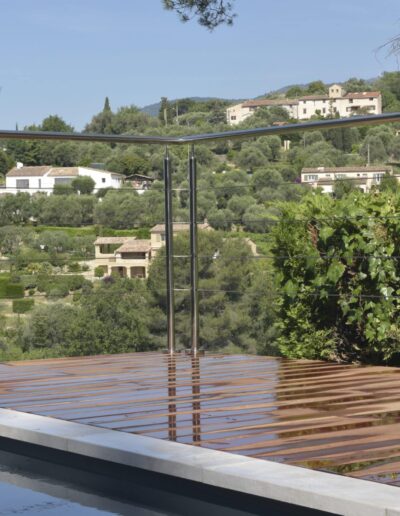 Garde-corps métallique au bord d’une terrasse en bois surplombant des collines arborées