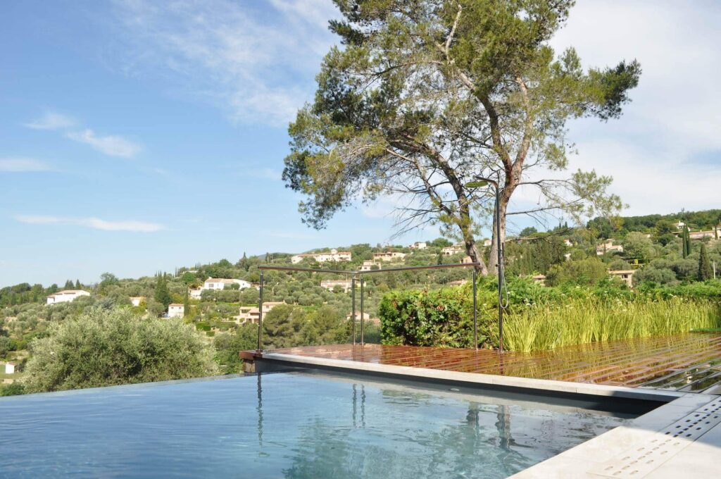 Infinity pool facing a mountain panorama, with a wooden dock