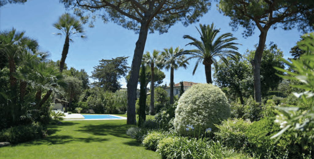 Lush garden dotted with topiary art, with a pool in the background