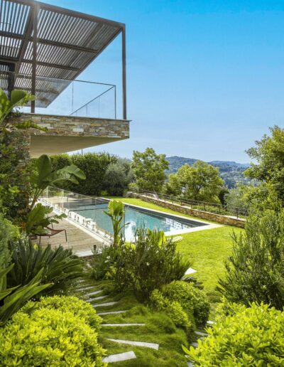 Overlook of a lush garden and modern pool with a panoramic hill view.