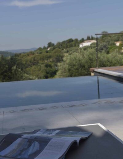 Magazine placed by an infinity pool with hillside views