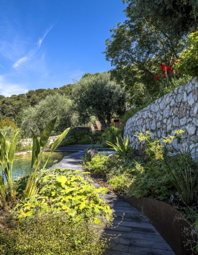 Natural pool surrounded by dense Mediterranean vegetation below stone terraces