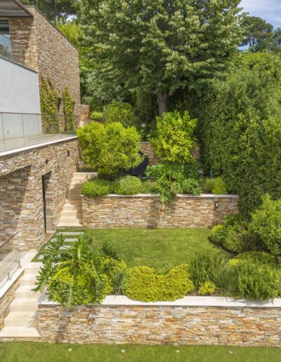 Drone view of a contemporary terraced garden with lush vegetation and sea panorama.