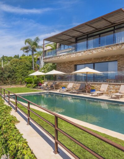 View of the landscaped garden with pool and large stone terrace at a contemporary villa in Mougins.