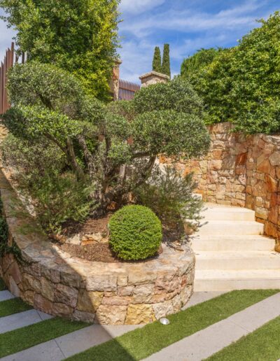 Series of planted terraces with stone steps surrounding a modern villa.