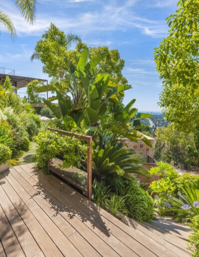 Terrasse en bois entourée de végétation tropicale avec vue dégagée sur la mer à Mougins.