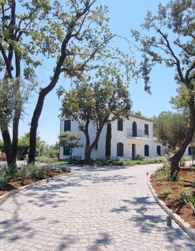 Finished paved driveway with Mediterranean plants leading to the renovated house