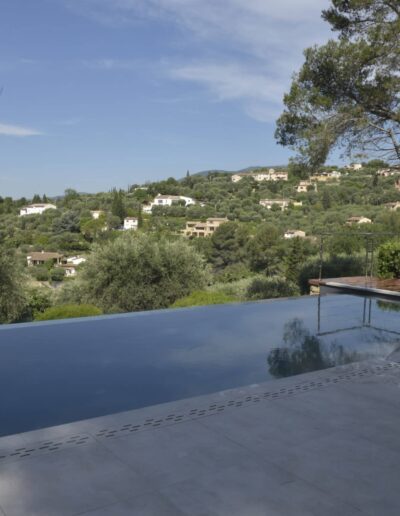 Piscine à débordement rénovée avec terrasse moderne et vue dégagée sur les collines