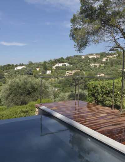 Piscine à débordement avec terrasse en bois et vue sur les collines verdoyantes