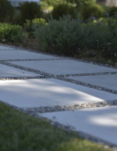 White stepping-stone path with gravel joints bordered by Mediterranean plantings