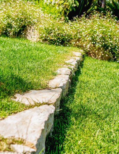 Natural stone edging separating the lawn from flowering beds