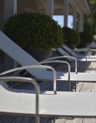 Close-up of a row of modern sun loungers aligned on a wooden deck near the pool