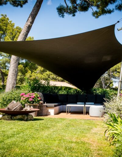Terrasse après aménagement paysager, avec banquette intégrée et voile d’ombrage valorisés par un jardin structuré