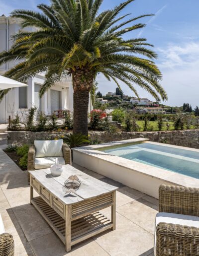 Terrasse aménagée avec mobilier extérieur, palmiers et bassin rectangulaire surplombant le paysage