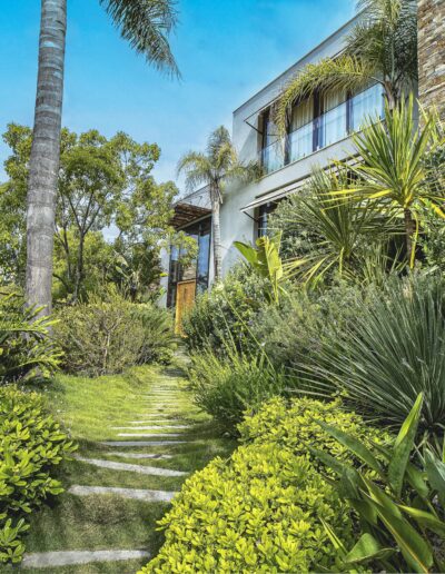 Landscaped path lined with palms, banana trees, and dense greenery leading to the villa.