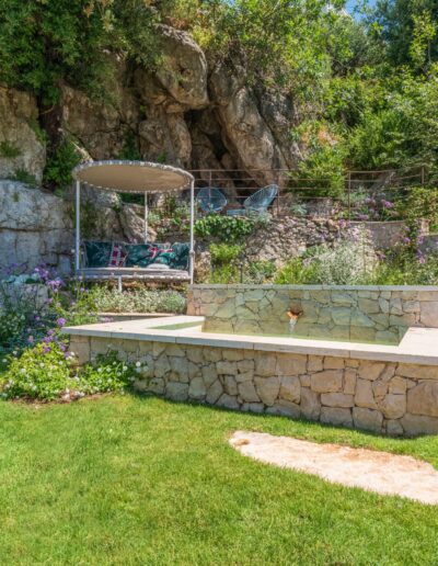 Completed landscape design with stone pool, retaining walls, and Mediterranean plants