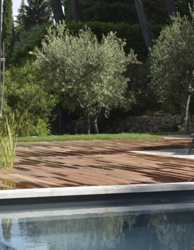 Wet wooden deck with Mediterranean vegetation and pool in the foreground