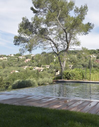 Wet wooden deck by an infinity pool with hillside views